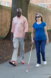 CVI staff member walking with blind woman with her identification cane