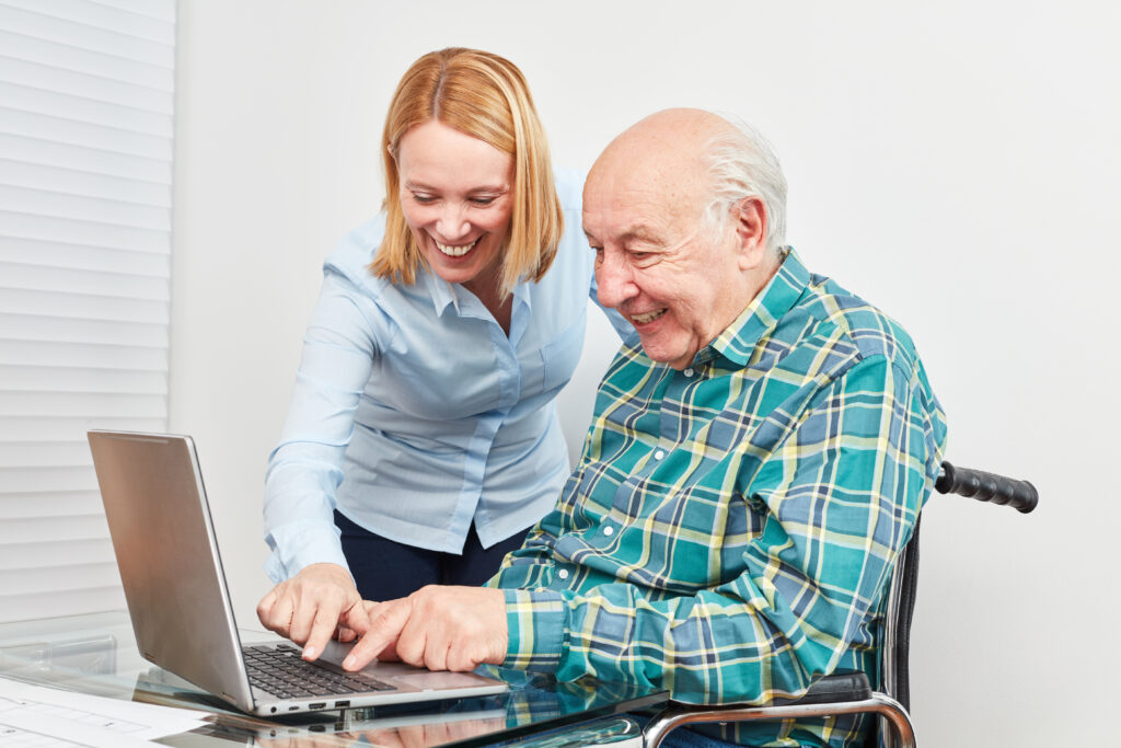 Adult female helping senior male use a laptop
