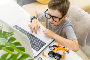 Young boy with glasses working on a laptop computer.