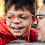Child with glasses smiling with his mom