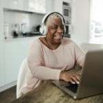 Woman smiling on computer and wearing headphones