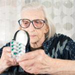 Older woman using magnifier to identify medication.